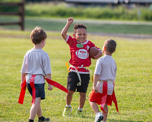 A youth celebrating his touchdown with his friends during Bitty Sports flag football.