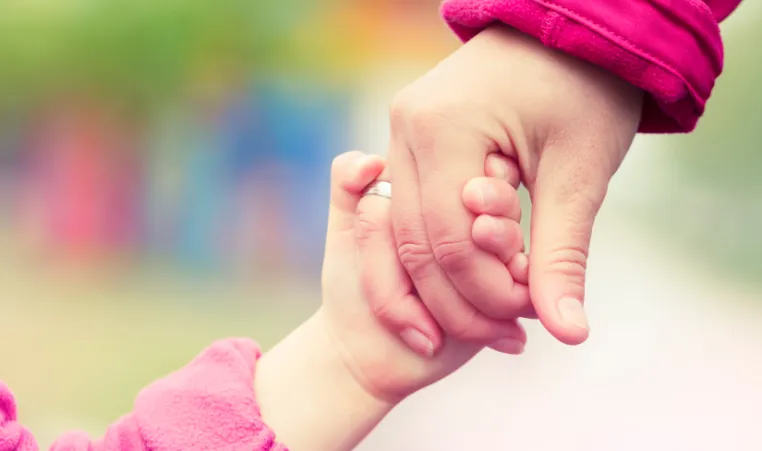 a close up of a youth and an adult holding hands