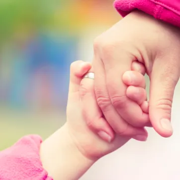 a close up of a youth and an adult holding hands
