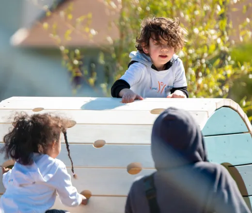 preschool children climb arch at North YMCA playscape on bright, spring day to celebrate grand opening