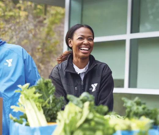 man and woman in YMCA jackets serve food at local food pantry
