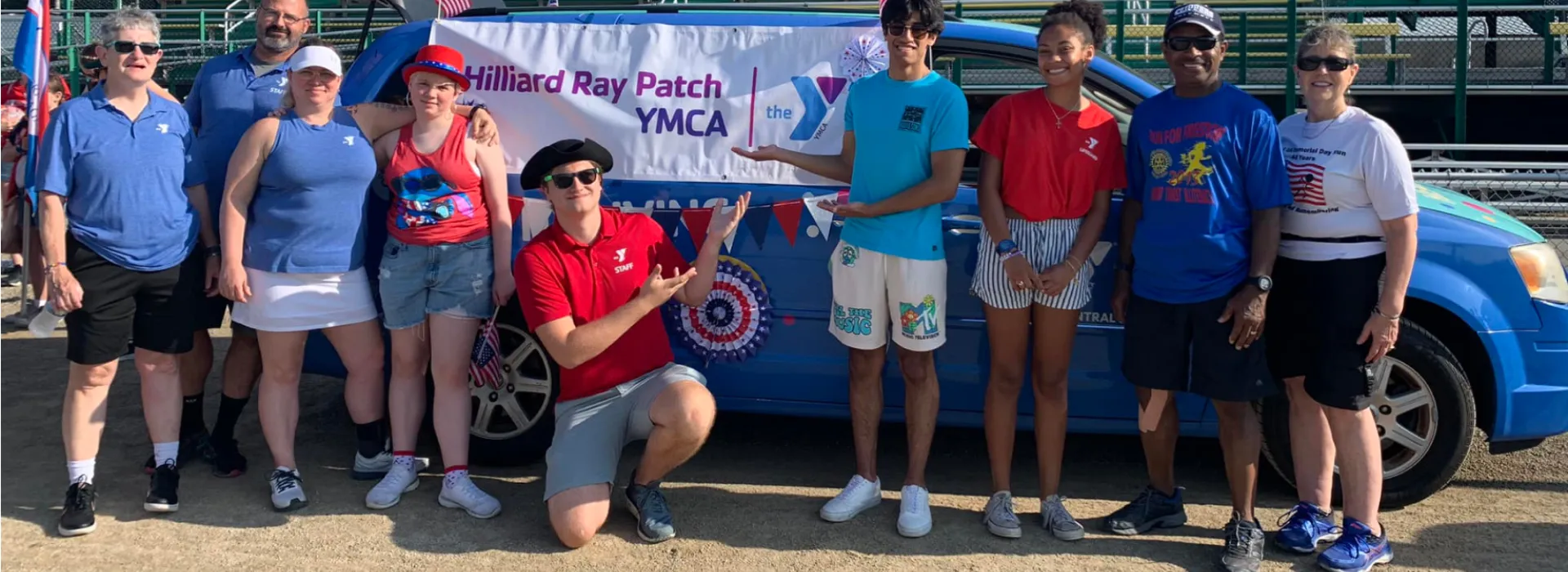 A group in front of a YMCA van outside ready to celebrate the 4th of July.