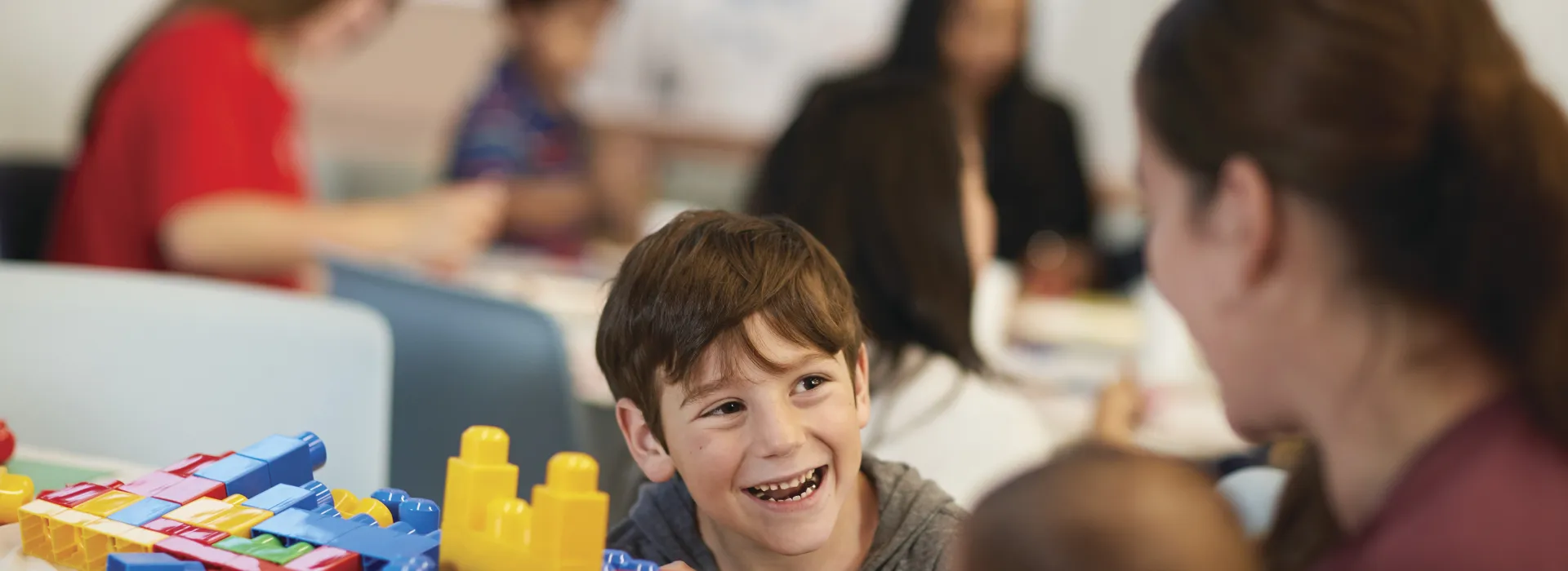 A youth enjoying time at family night while he builds with blocks.